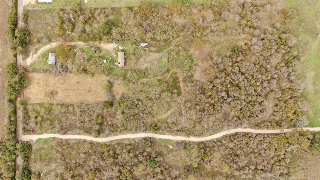 870 Wagoner Road, Waco, TX 76705 Aerial perspective featuring expansive acreage, dense woodland cover, a primary structure, and an unpaved access road