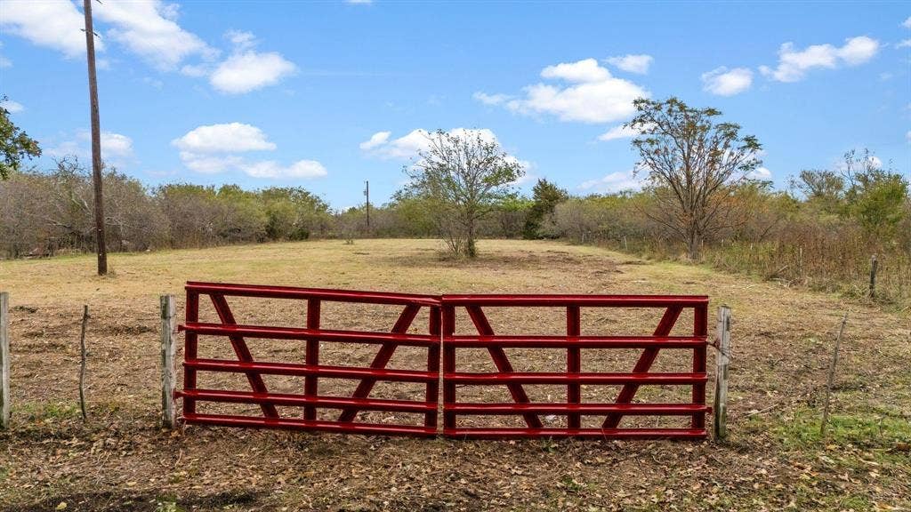 870 Wagoner Road, Waco, TX 76705 Expansive acreage featuring a metal tubular gate, wire fencing, and mature trees