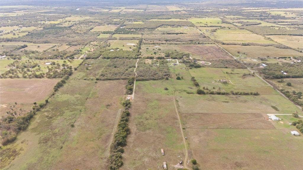 870 Wagoner Road, Waco, TX 76705 Aerial perspective of expansive acreage featuring open pastureland, clusters of mature trees, and unpaved access paths