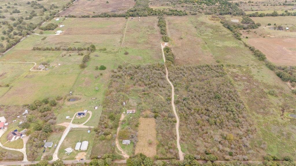 870 Wagoner Road, Waco, TX 76705 Expansive acreage featuring cleared pasture land, clusters of mature trees, natural water features, and an unpaved access path