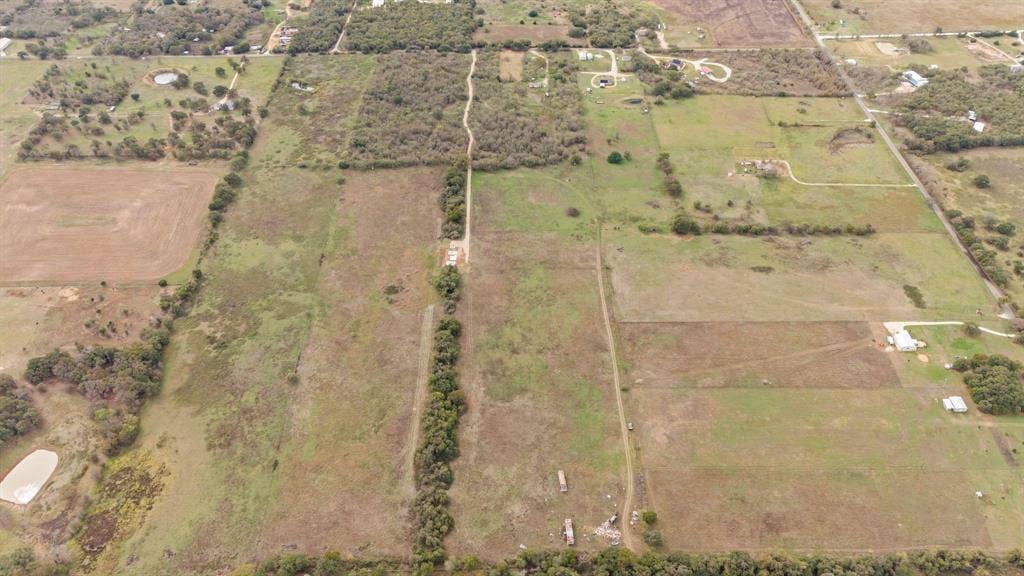 870 Wagoner Road, Waco, TX 76705 Expansive acreage featuring cleared pasture land, dense clusters of mature trees, and established unpaved access paths