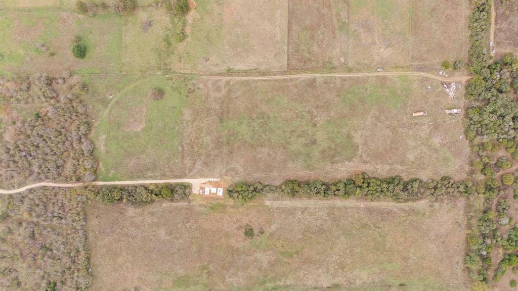 870 Wagoner Road, Waco, TX 76705 Aerial perspective of expansive acreage featuring open pasture land, dense mature tree clusters, and a gravel access road