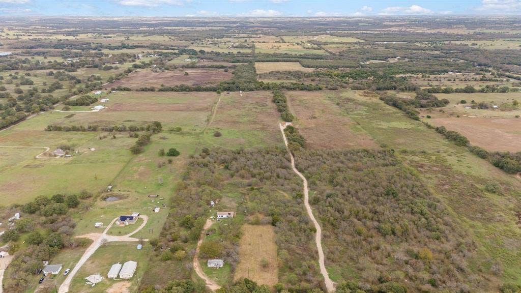 870 Wagoner Road, Waco, TX 76705 Expansive acreage featuring cleared pasture, areas of dense mature trees, and unpaved private access paths