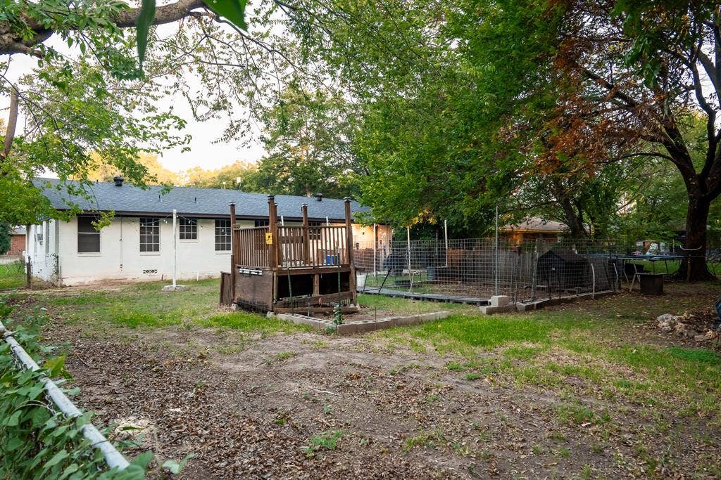 Spacious backyard featuring a wood deck, perimeter wire fencing, and mature trees