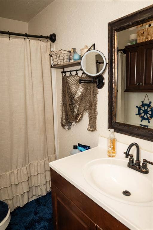 Dark wood vanity with a white countertop and oval undermount sink featuring an oil-rubbed bronze dual-handle faucet, wall-mounted adjustable mirror, and a framed mirror above the vanity