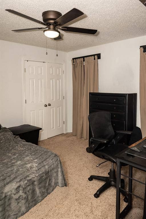Room featuring neutral carpeting, double-panel closet doors, and a ceiling-mounted fan with integrated lighting