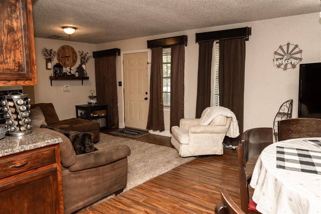 Wood-finish flooring, dark wood-tone cabinetry, and windows topped with decorative cornices