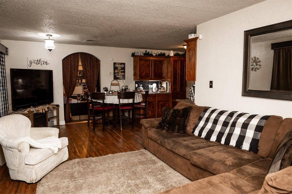 Interior space featuring wood-finish flooring, stained wood cabinetry, and a distinctive arched doorway