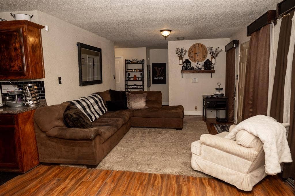 Living area featuring wood-finish flooring, carpeted flooring, and wood cabinetry with a tile backsplash