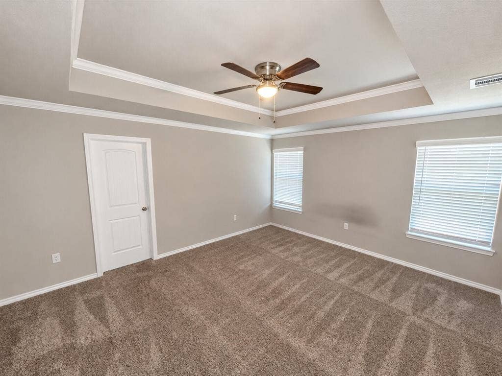 1306 Campbelton Drive, Temple, TX 76504 Tray ceiling featuring crown molding, neutral carpeting, multi-paneled door, and central ceiling fan with integrated lighting
