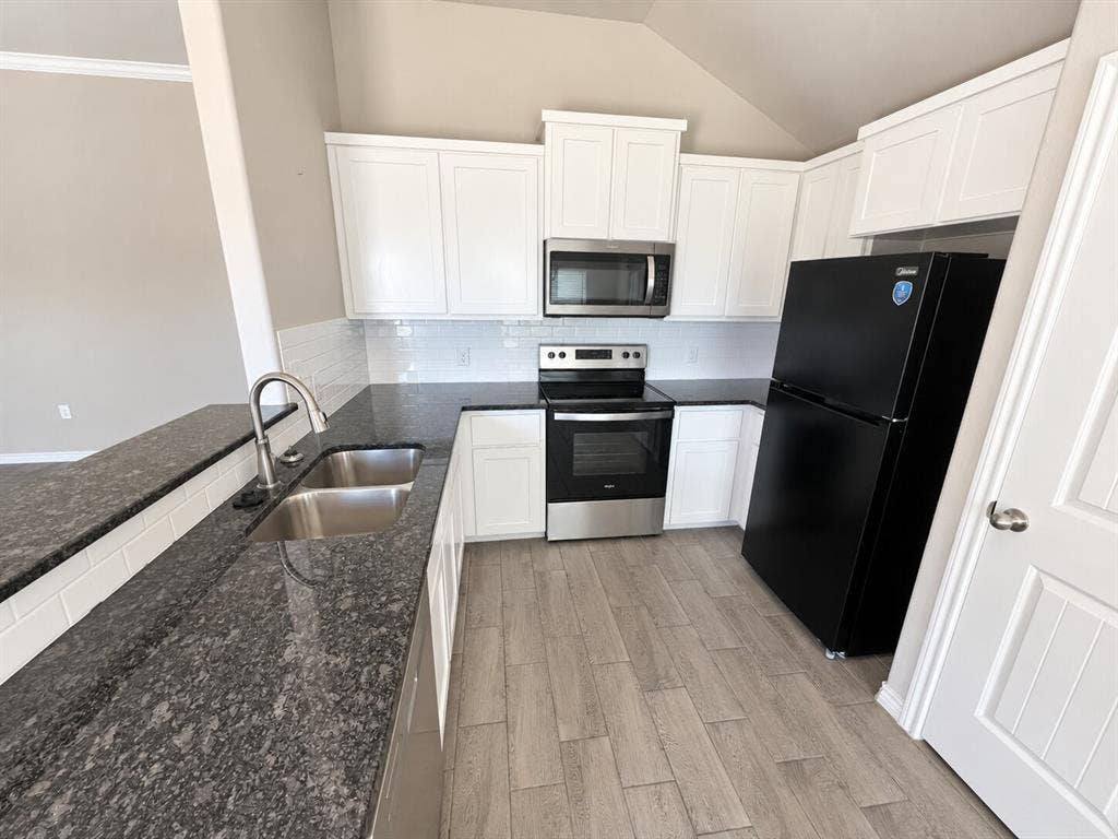 1306 Campbelton Drive, Temple, TX 76504 Kitchen featuring white shaker-style cabinetry, dark stone countertops, subway tile backsplash, stainless steel appliances, and wood-finish flooring