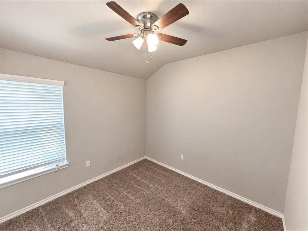 1306 Campbelton Drive, Temple, TX 76504 Neutral-toned room featuring a vaulted ceiling, textured carpeting, window blinds, and a multi-blade ceiling fan with integrated lighting