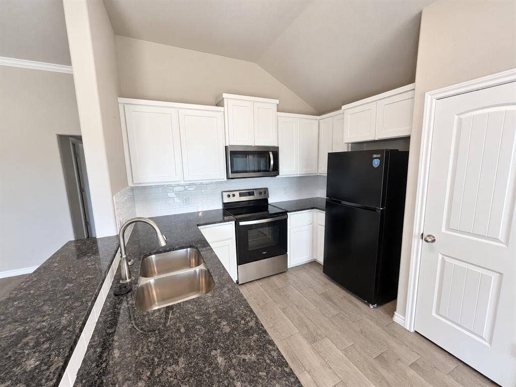 1306 Campbelton Drive, Temple, TX 76504 Kitchen featuring white shaker-style cabinetry, dark stone-finish countertops, subway tile backsplash, stainless steel appliances, and wood-finish flooring