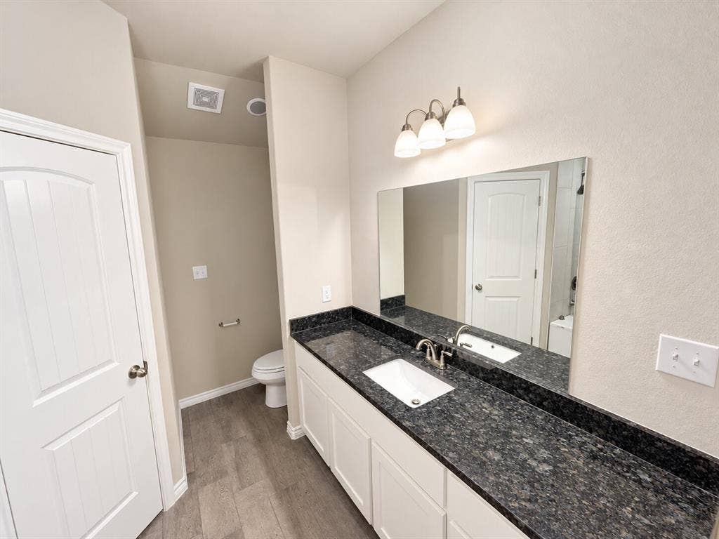 1306 Campbelton Drive, Temple, TX 76504 Bathroom featuring a dual-toned vanity with dark stone countertop, integrated sink, white shaker-style cabinetry, and a full-width wall-mounted mirror