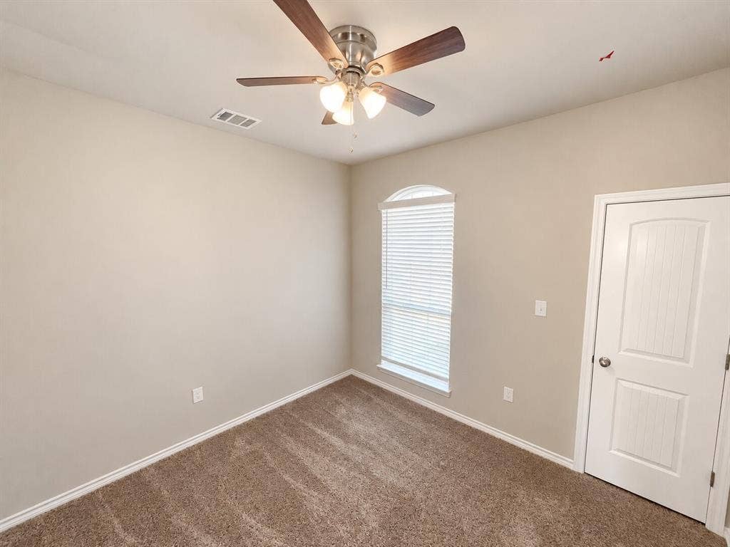 1306 Campbelton Drive, Temple, TX 76504 Neutral interior room featuring neutral-toned carpeting, a multi-blade ceiling fan with integrated lighting, a single-panel arched window, and a two-panel interior door