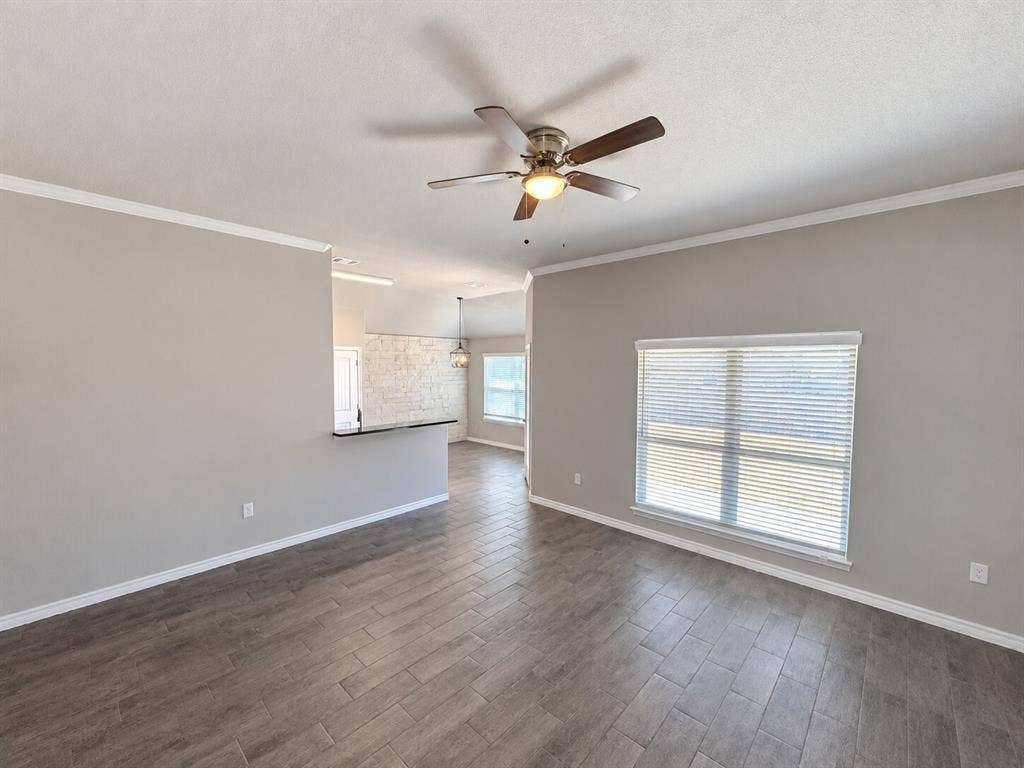 1306 Campbelton Drive, Temple, TX 76504 Open interior space featuring wood-finish tile flooring, neutral wall tones, a ceiling fan with integrated lighting, and a breakfast bar
