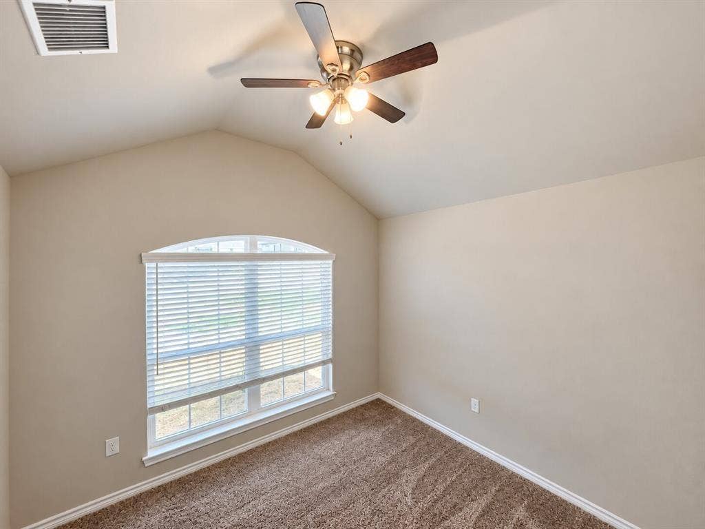 1306 Campbelton Drive, Temple, TX 76504 Vaulted ceiling featuring a central brushed-nickel ceiling fan with integrated lighting, a prominent arched window, and wall-to-wall carpeting