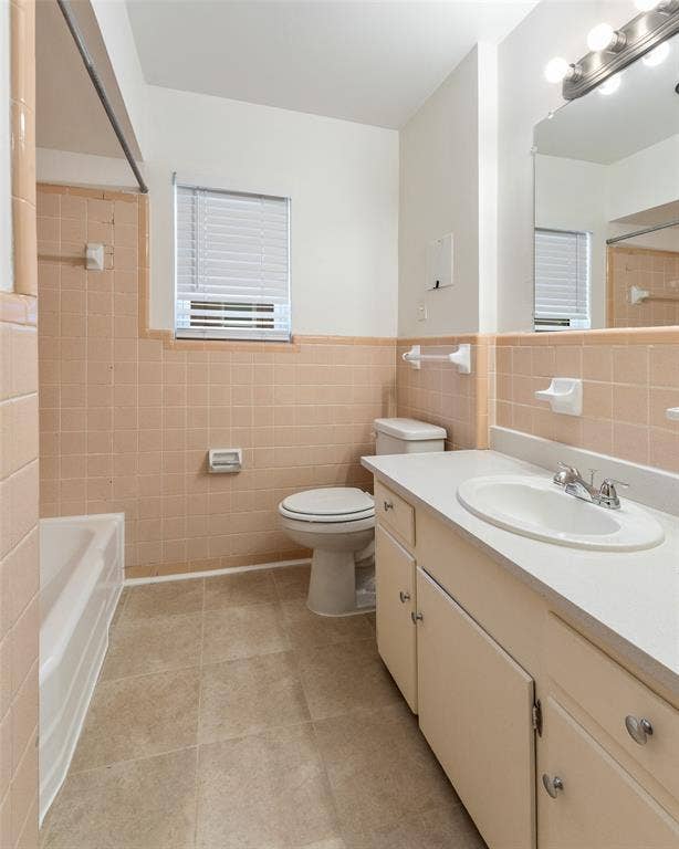 11038 Wyatt, Dallas, TX 75218 Bathroom featuring ceramic tile wall surrounds, a built-in vanity cabinet with a solid surface countertop, an integrated oval sink, and a multi-light fixture