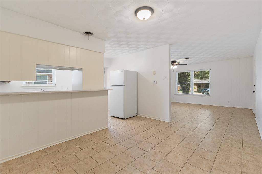 11038 Wyatt, Dallas, TX 75218 Kitchen area featuring a pass-through opening to the common space, neutral tile flooring, light-toned cabinetry, and a ceiling-mounted light fixture