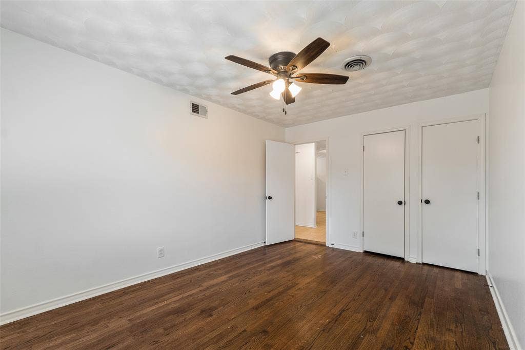 11038 Wyatt, Dallas, TX 75218 Room featuring wood-finish flooring, textured ceiling, central ceiling fan with integrated lighting, and dual built-in closets