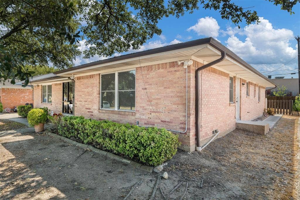 11038 Wyatt, Dallas, TX 75218 Single-story exterior featuring a light-toned brick facade, a low-slope roofline, and framed glass windows