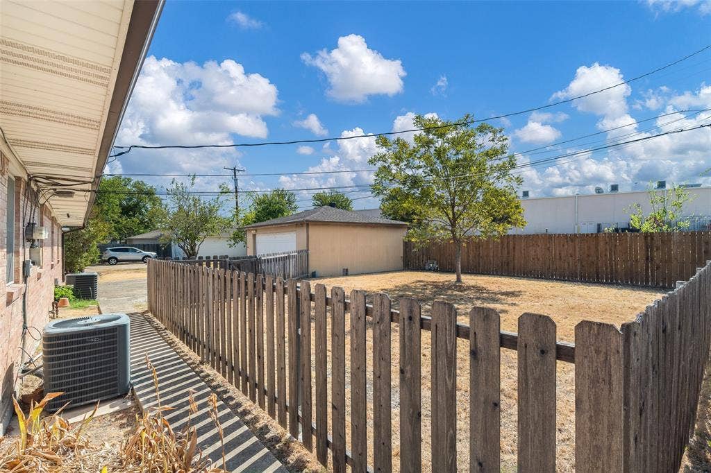 11038 Wyatt, Dallas, TX 75218 Fenced backyard featuring a detached garage, mature tree, and exterior central air conditioning unit