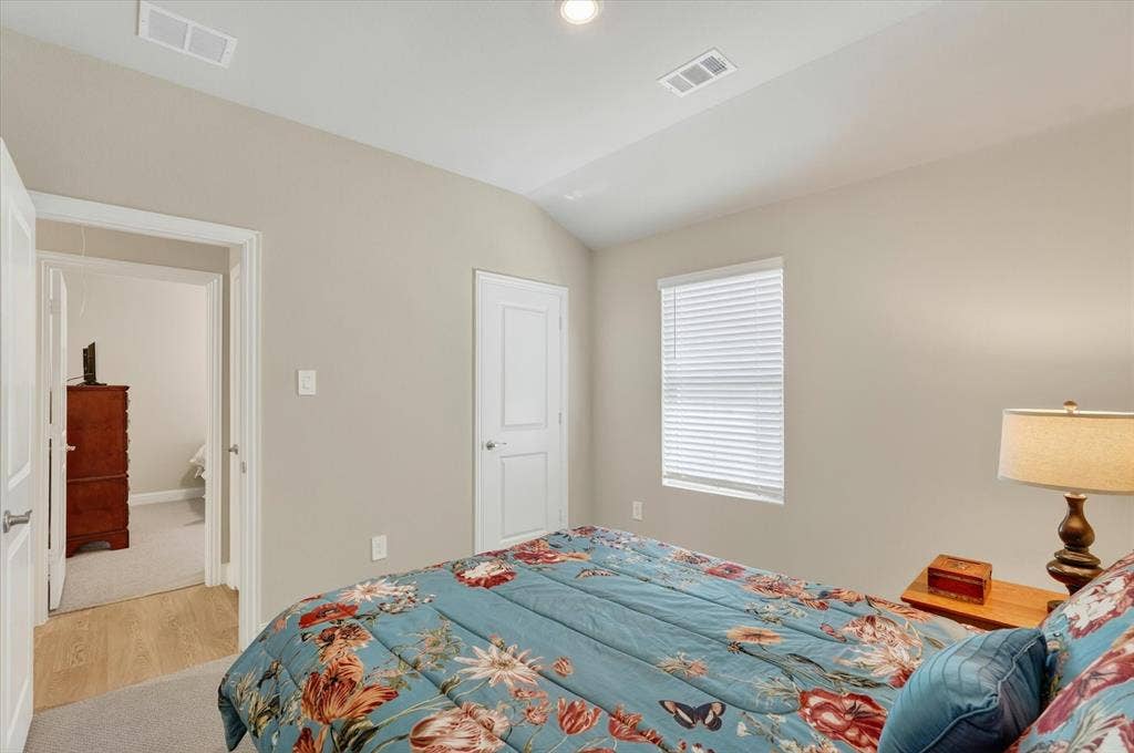 903 Edgehurst Drive, Princeton, TX 75071 Bedroom with vaulted ceiling, light beige wall paint, single window with horizontal blinds, and a white two-panel interior door