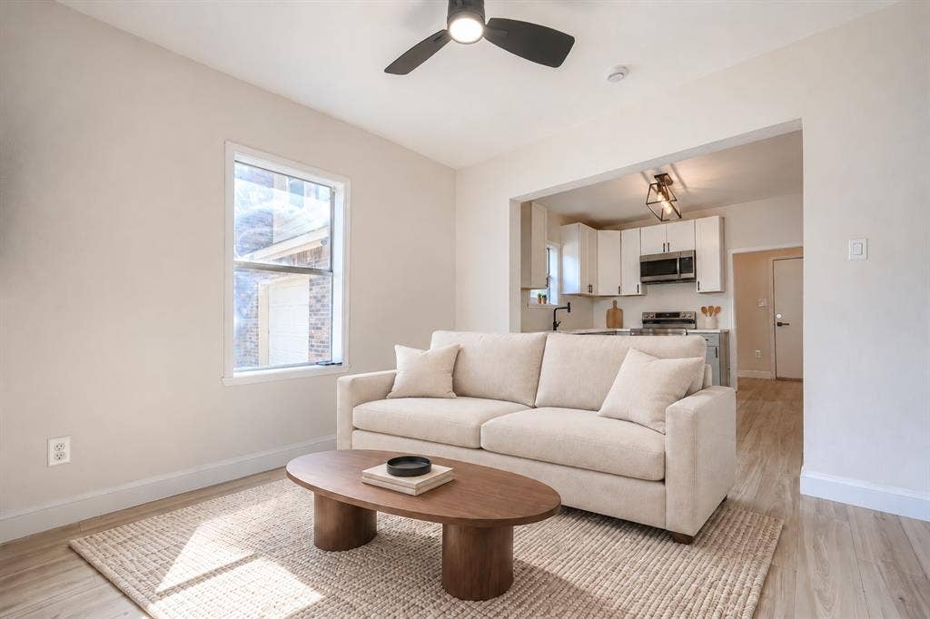 Neutral walls featuring wood-finish flooring, a contemporary ceiling fan, and white cabinetry with integrated stainless steel appliances