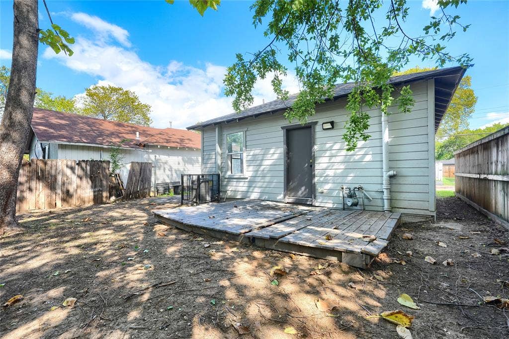 Rear exterior featuring horizontal lap siding, a ground-level wood deck, and wood privacy fencing