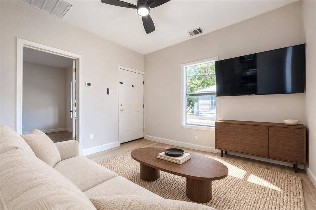 Neutral-toned interior featuring wood-finish flooring, a contemporary matte black ceiling fan, and a single-hung window with a white frame