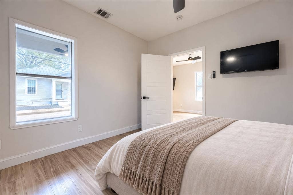 Room interior featuring wood-finish flooring, a single-panel interior door with matte black hardware, and a ceiling fan
