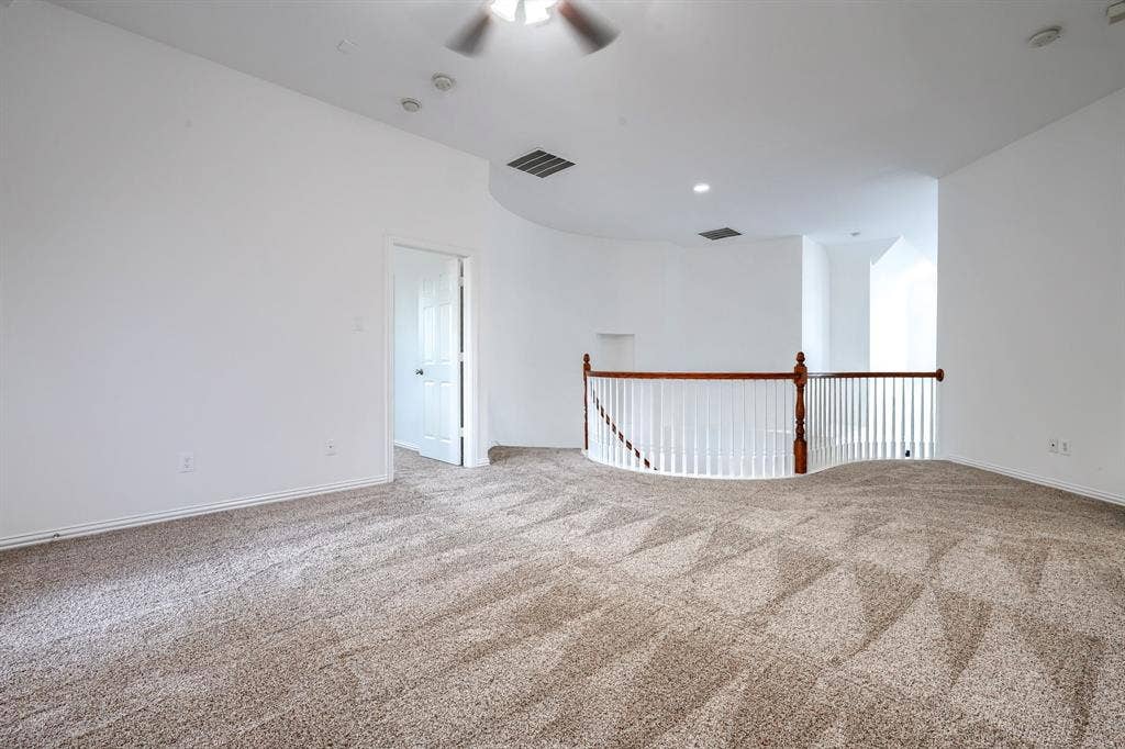 1127 Valley Vista Drive, Irving, TX 75063 Open-concept space featuring wall-to-wall carpeting, high ceilings, and a curved balcony with a wood-finished railing and white balusters