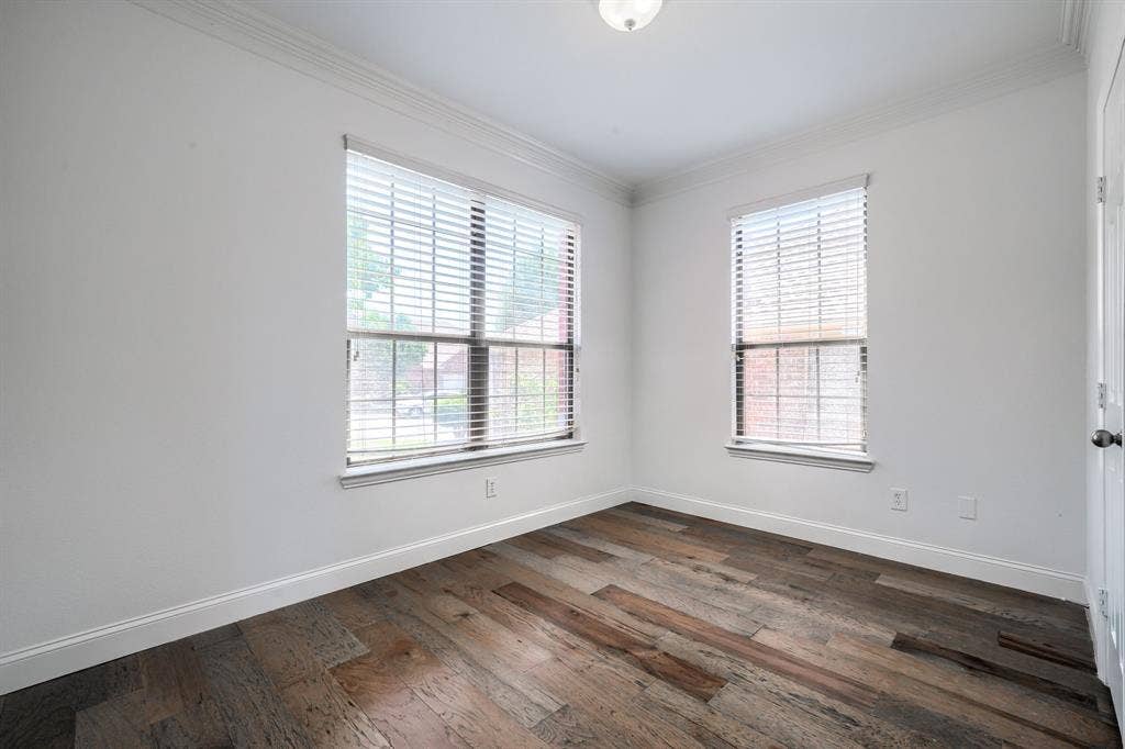 1127 Valley Vista Drive, Irving, TX 75063 Room featuring wood-finish flooring, crown molding, and two windows with horizontal blinds