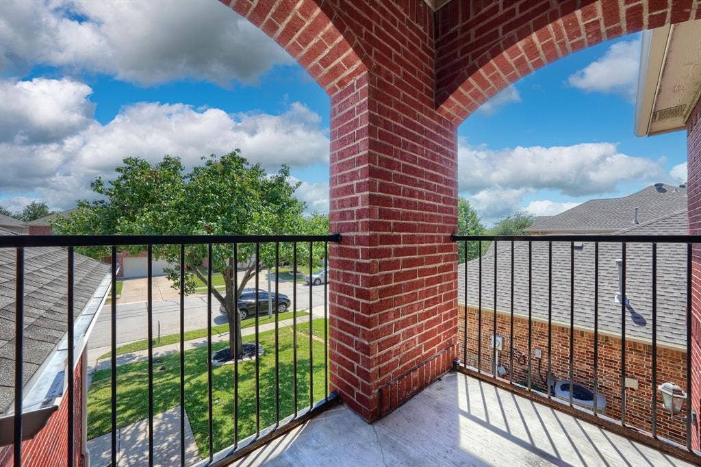 1127 Valley Vista Drive, Irving, TX 75063 Covered brick balcony featuring an arched brick pillar and black metal railing