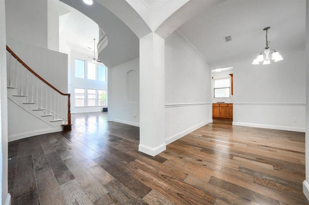 1127 Valley Vista Drive, Irving, TX 75063 Foyer featuring wood-finish flooring, a staircase with a wooden handrail, multi-story windows, chair rail molding, and a chandelier
