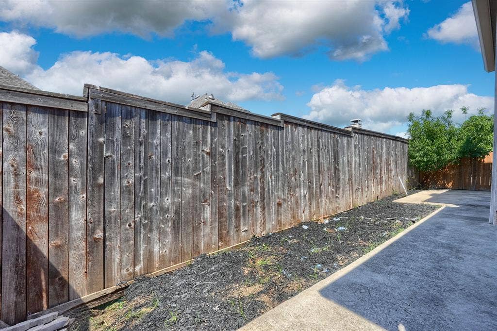 1127 Valley Vista Drive, Irving, TX 75063 Full-height wood privacy fencing with cap rail, concrete hardscaping, and mulched landscaping border