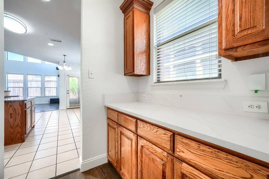 1127 Valley Vista Drive, Irving, TX 75063 Built-in cabinetry with natural wood finish, stone-surface countertop, and window with horizontal blinds