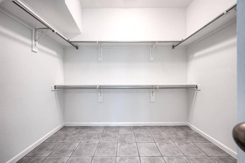 1127 Valley Vista Drive, Irving, TX 75063 Walk-in storage space featuring ceramic tile flooring, multi-level metal hanging rods, and integrated shelving supports