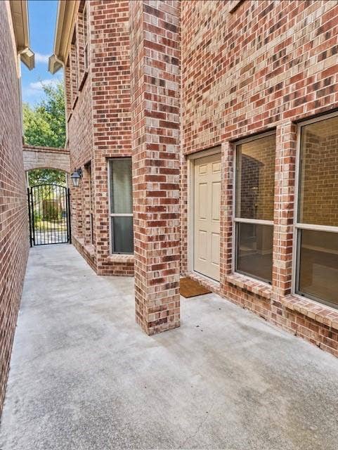 2002 Downing Street, Allen, TX 75013 Full-brick exterior facade featuring a concrete patio, paneled entry door, vertical windows with brick sills, and a metal security gate