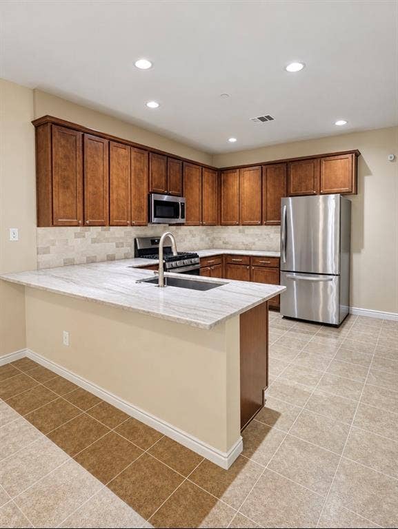 2002 Downing Street, Allen, TX 75013 Kitchen featuring wood cabinetry, stone-surface countertops, tile backsplash, stainless steel appliances, and ceramic tile flooring