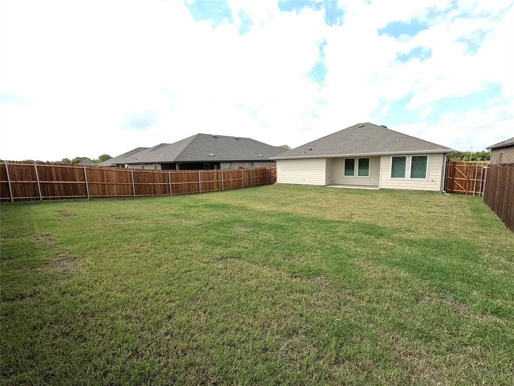 4017 Bronco Drive, Princeton, TX 75407 Expansive backyard featuring a large grass lawn, perimeter wood fencing, and a concrete patio slab