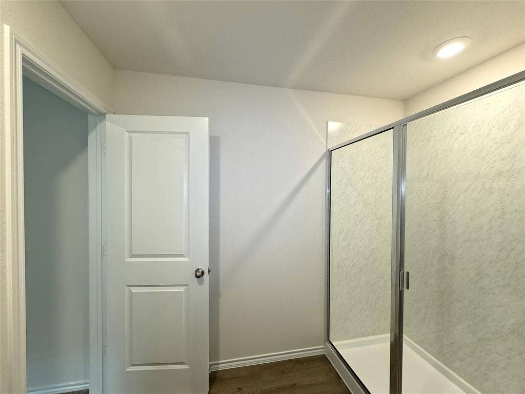 4017 Bronco Drive, Princeton, TX 75407 Shower enclosure featuring a chrome frame and surround, integrated recessed ceiling lighting, and wood-finish flooring