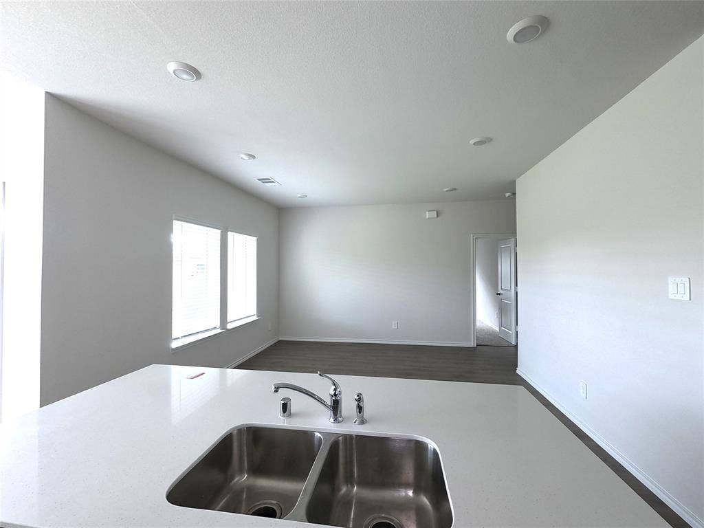 4017 Bronco Drive, Princeton, TX 75407 Solid surface countertop with a stainless steel double-basin undermount sink, high-arc faucet, recessed lighting, and wood-finish flooring
