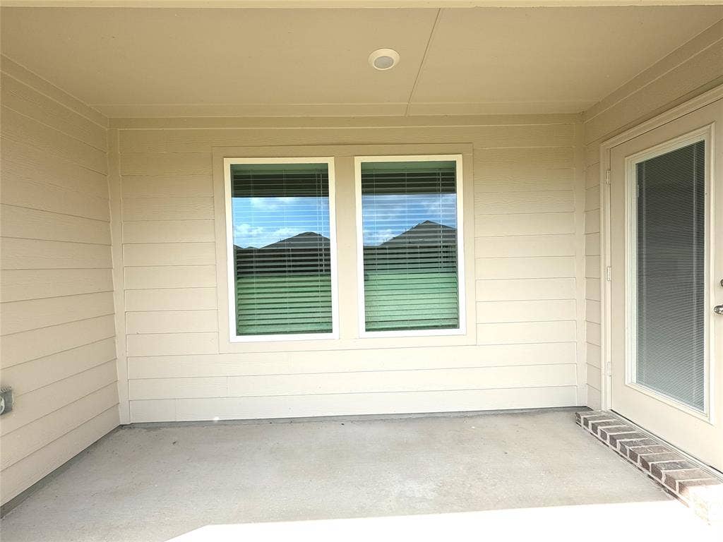 4017 Bronco Drive, Princeton, TX 75407 Covered patio featuring concrete flooring, horizontal siding, dual windows, and an exterior door with inset glass