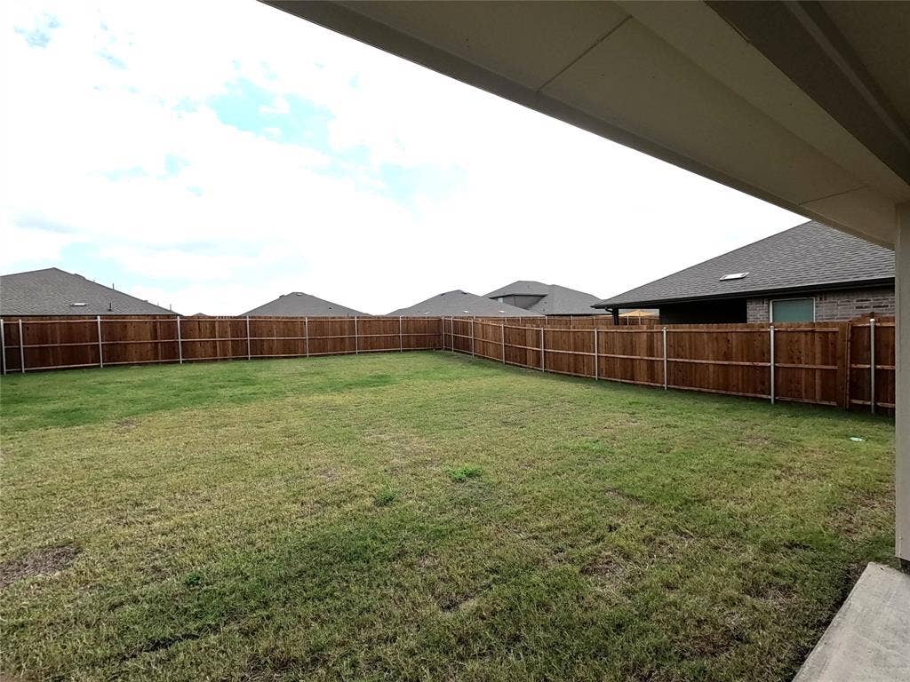 4017 Bronco Drive, Princeton, TX 75407 Backyard featuring a grass lawn, full-height wood fencing, and a concrete patio slab