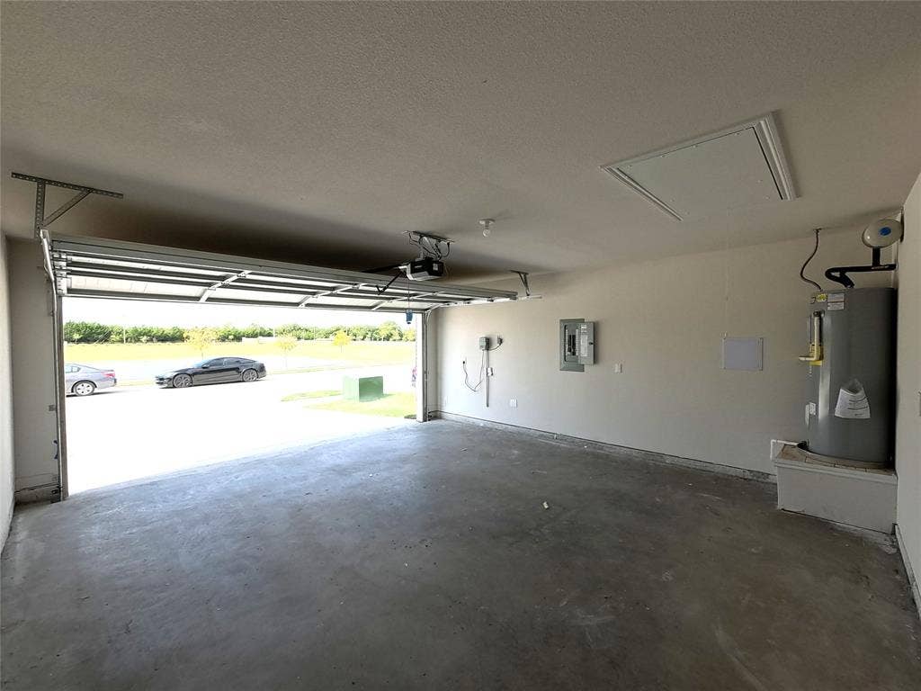4017 Bronco Drive, Princeton, TX 75407 Attached two-car garage featuring a concrete floor, automated overhead door, electrical panel, and elevated water heater platform