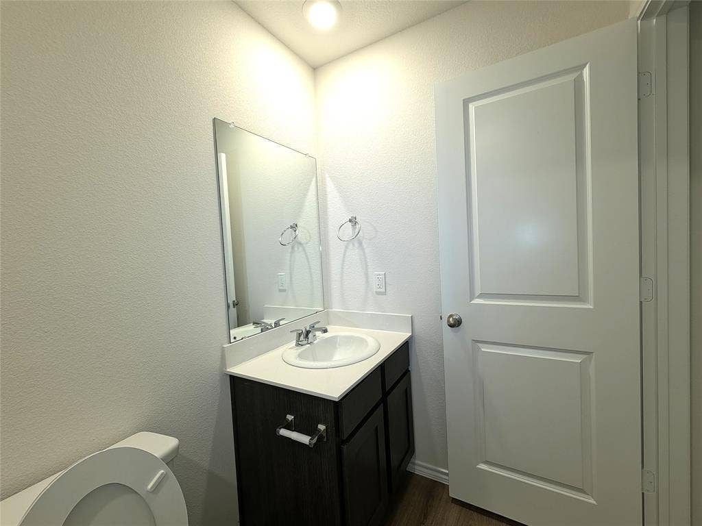 4017 Bronco Drive, Princeton, TX 75407 Single-sink vanity featuring a dark-finish cabinet, integrated countertop with oval basin, wall-mounted mirror, and brushed-metal fixtures