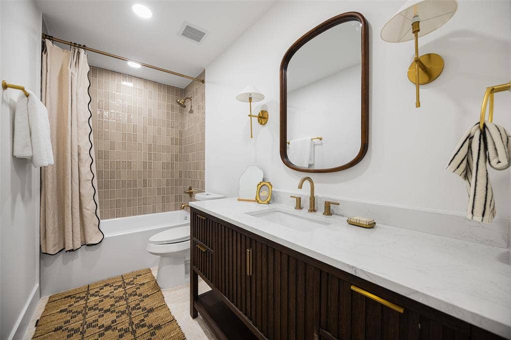 This tastefully renovated full bathroom features a spacious vanity, elegant finishes, and a beautifully tiled walk-in shower. (This photo has been digitally enhanced.)