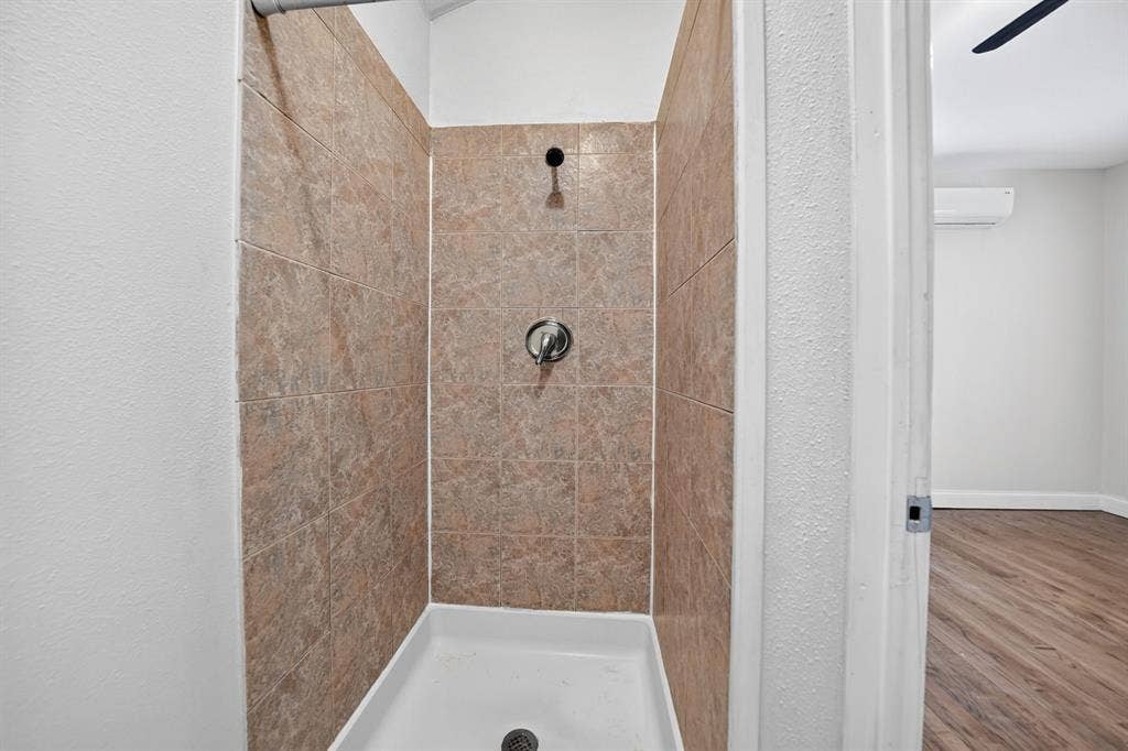 Shower stall featuring tiled shower, a white acrylic basin, and a single-handle chrome fixture