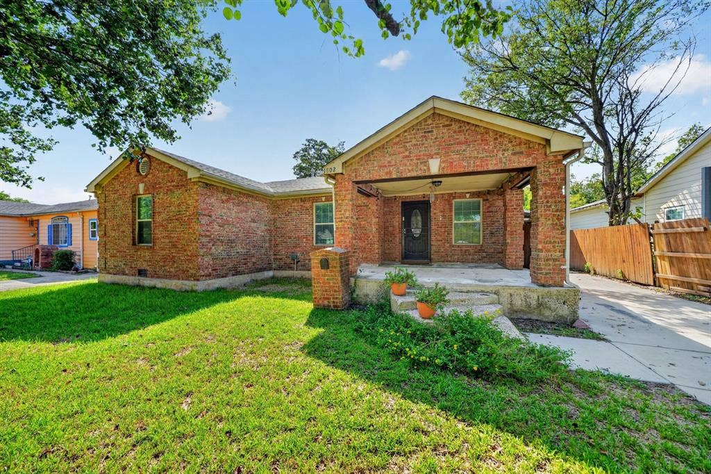 Single-story brick exterior featuring a covered front porch, concrete entryway, gable roofline, and concrete driveway